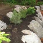 Boulders placed to retain flower beds in retaining wall